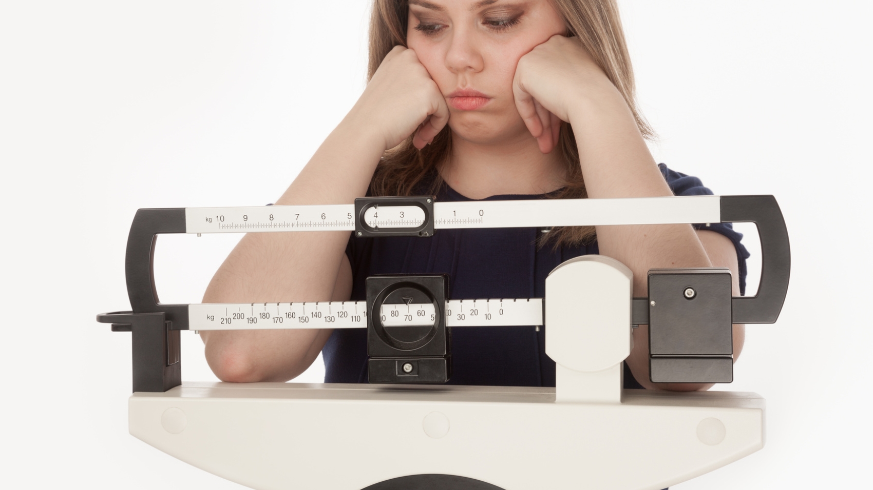 Young woman dissapointed on a medical weight scale.